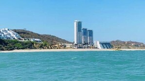 Un hotel sulla costa con vista sulla spiaggia, un edificio grande e un molo che si protende nell'acqua.