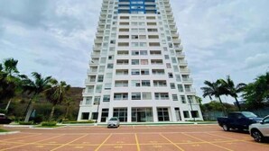 Un edificio a più piani con tetto piatto, ampie finestre e un parcheggio di fronte.