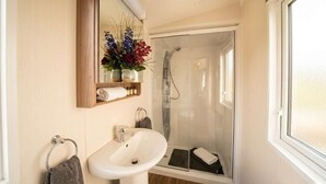 A bathroom with a sink, mirror, and shower. - 3BR Premium Caravan | Near Edinburgh |Parking|WiFi (Port Seton)