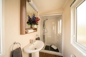 A bathroom with a sink, mirror, and shower.