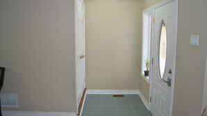 A hallway with a door, a potted plant, and a vent on the wall.