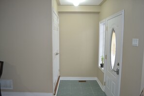 A hallway with a door, a potted plant, and a vent on the wall. - 3 BEDROOM FULLY FURNISHED HOUSE DOWNTOWN WHITBY (WHITBY)