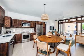 A modern kitchen with dark wood cabinets, stainless steel appliances, and a dining area with wicker chairs.