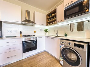 Una cocina moderna con armarios blancos, electrodomésticos de acero inoxidable, un horno Bosch, un lavavajillas Bosch y una lavadora Bosch.