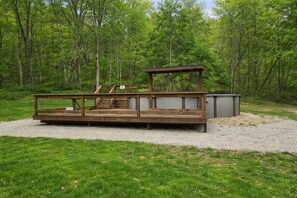 A wooden deck with a bench and a small shelter in a wooded area.