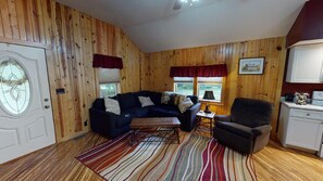 A cozy room with wooden walls, a dark blue sofa, a patterned rug, and a small table.