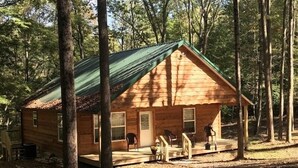A wooden cabin with a porch, surrounded by trees. - Scotts Creek Cabins - Hilltop (Logan)