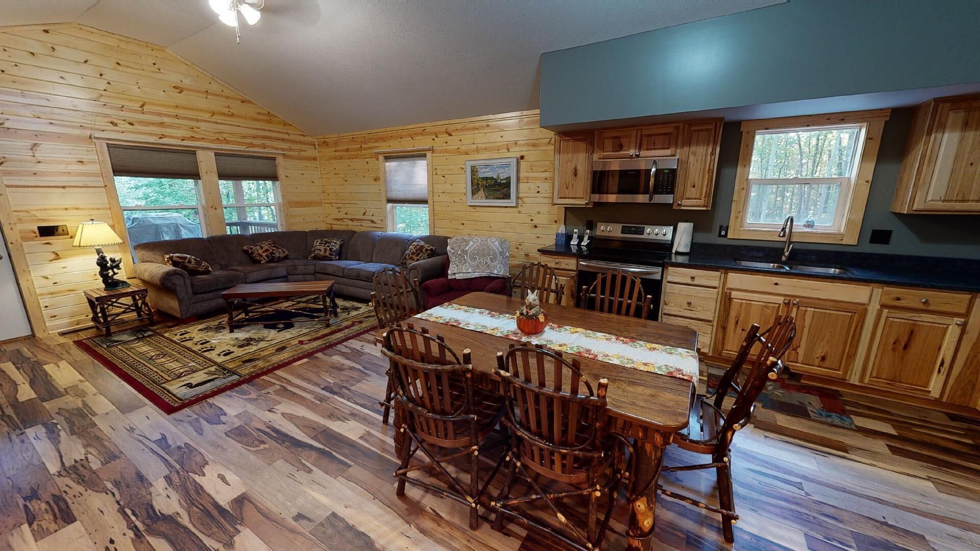 A log cabin interior with a living room, dining area, and kitchen.