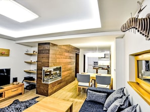 Una sala de estar moderna con chimenea, muebles de madera y un comedor.