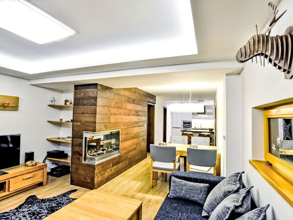 Uma sala de estar moderna com lareira, móveis de madeira e um espaço para refeições.