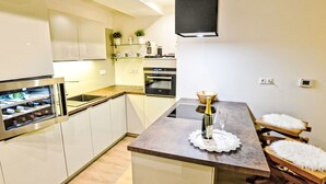 A modern kitchen with a central island, built-in oven, and a wine cooler. - Luxury Wellness by Interhome (Rokytnice nad Jizerou)