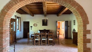 Un'area ristorazione con tavolo e sedie in legno, un lampadario e archi in mattoni.