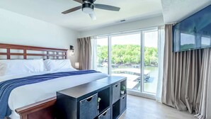 A hotel room with a bed, a ceiling fan, a TV, a large window, and a balcony. - Sunset Lakefront Retreat with Luxe Upgrades (Osage Beach)