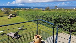 A balcony with a view of a vineyard, a stone wall, and a metal railing. - Panoramic Sea View Retreat in Brittany (Lampaul-Plouarzel)