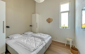 A bedroom with a bed, a bedside table, a window, and a wall-mounted heart decoration.