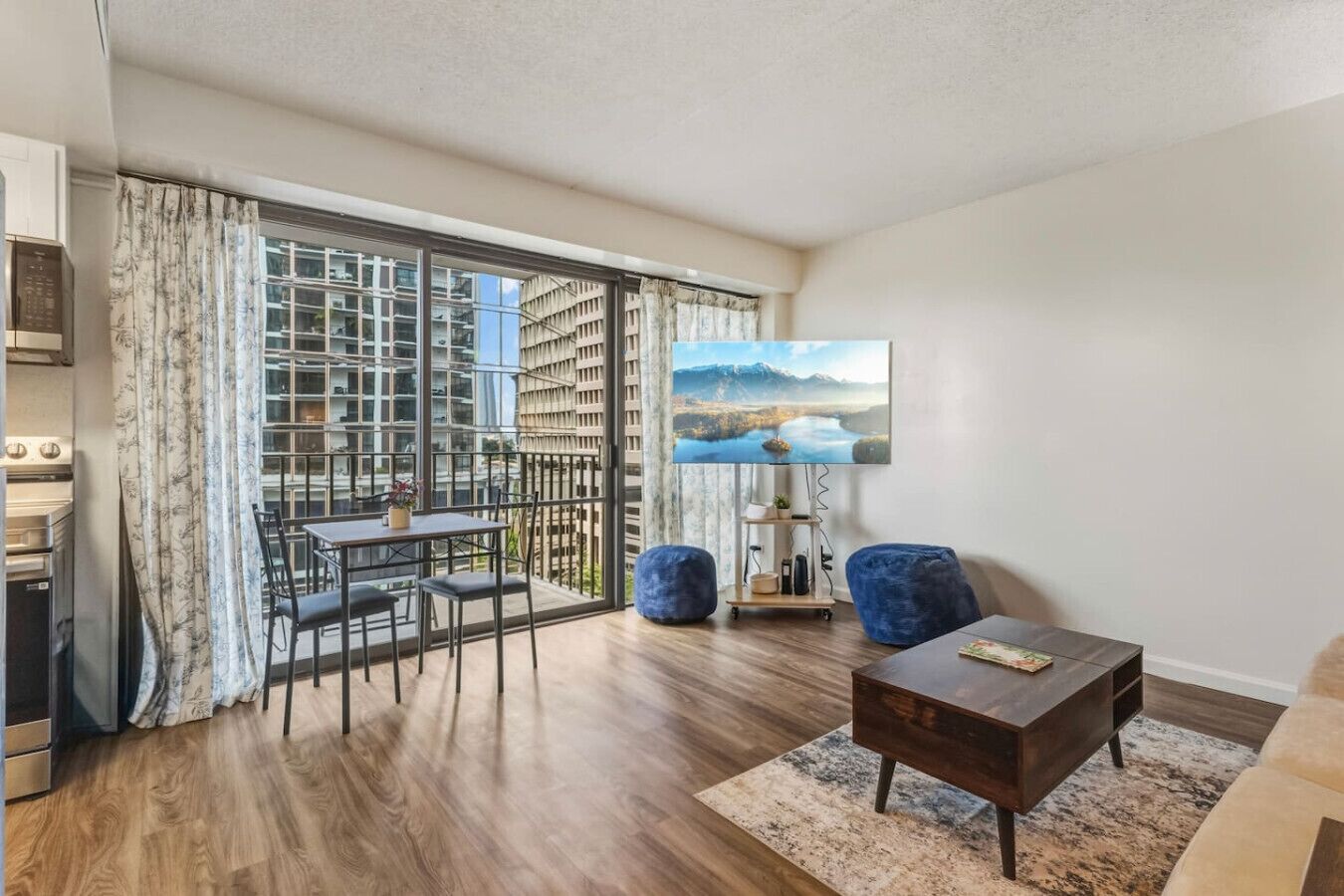A modern apartment with a dining area, a sofa, a coffee table, and a large window with a city view.
