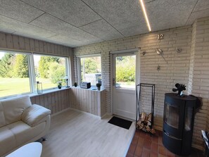 A modern living room with a white sofa, a fireplace, and a view of the outdoors. - Renovated holiday home with hot tub Marielyst (Væggerløse)
