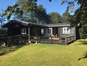 Eine Holzhütte mit Veranda, einer Terrasse und einer kleinen Sitzgelegenheit im Freien.
