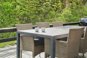 Eine Terrasse mit Tisch und Stühlen, umgeben von viel Grün.