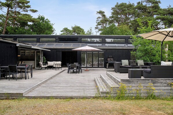 A modern outdoor patio with a dining area, seating, and a covered section.