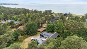 Een woongebied met huizen, omringd door dicht bos, een strand op de achtergrond en een helder uitzicht op de zee.