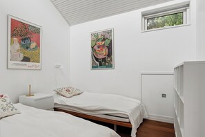 Een slaapkamer met twee bedden, een nachtkastje, een raam en twee wanddecoraties.