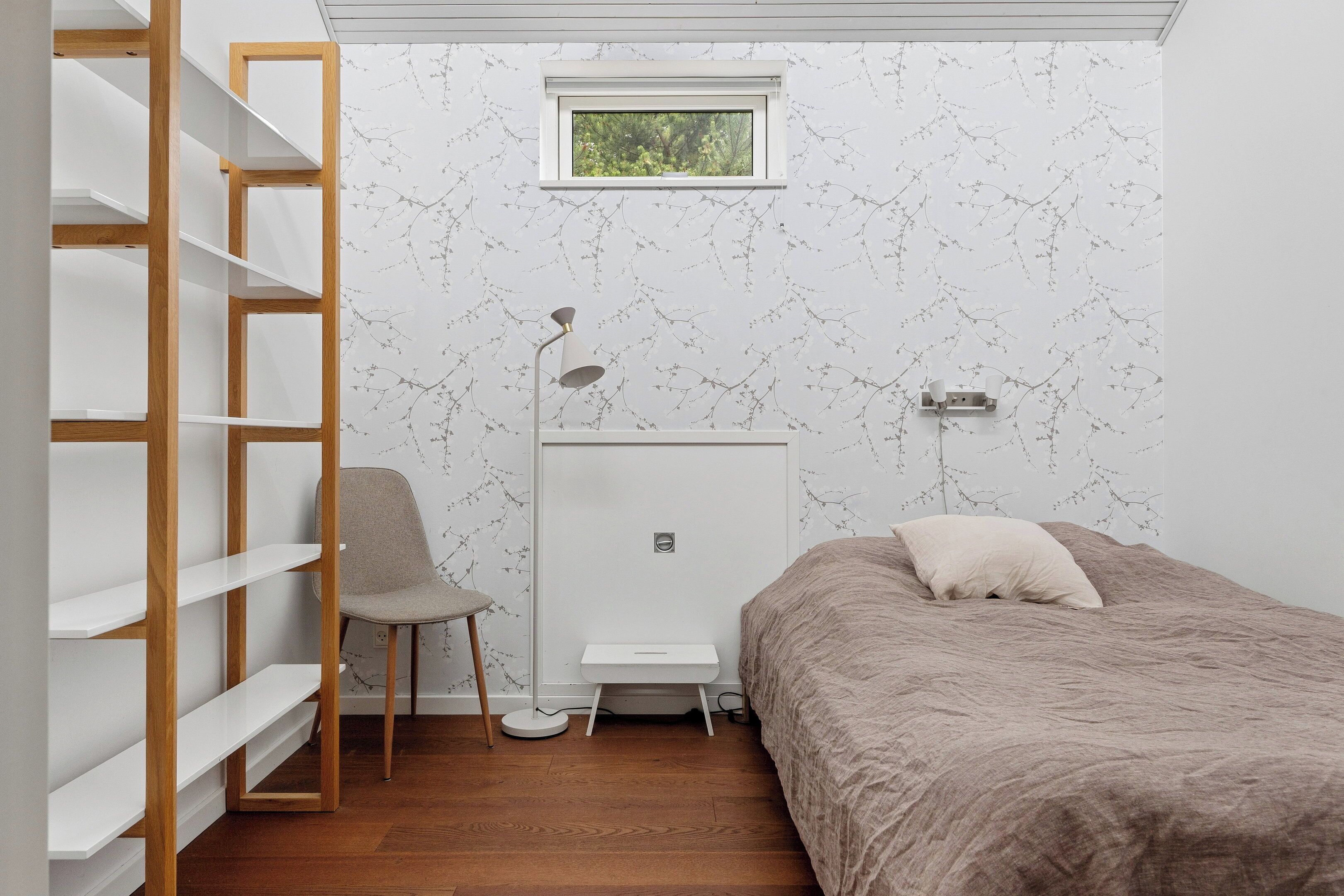 A bedroom with a bed, a chair, a desk, and a wardrobe.
