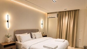 A modern hotel room with a large bed, bedside tables, a wall-mounted air conditioner, and a window with curtains. - 10-Mins from Cairo Airport, Garden Oasis (Cairo Governorate)