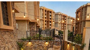 An outdoor seating area with wicker chairs and a table, surrounded by a stone wall and greenery. - 10-Mins from Cairo Airport, Garden Oasis (Cairo Governorate)
