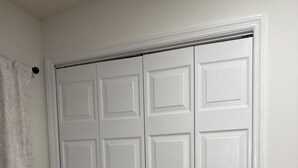 A white closet with multiple doors and a towel hanging on the left. - Tampa Cozy Spot (Tampa)