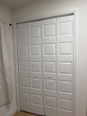 Un armario blanco con varias puertas y una toalla colgando a la izquierda.
