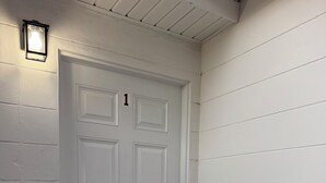 A white door with a number 1 sign, a doorbell, and a welcome mat. - Tampa Cozy Spot (Tampa)