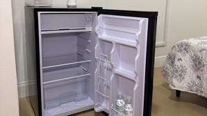 A compact refrigerator with a freezer compartment, a water dispenser, and a power outlet on the wall. - Tampa Cozy Spot (Tampa)