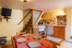 Eine kleine Küche mit Mikrowelle, Herd und Spüle. Ein Esstisch mit Stühlen ist für zwei Personen gedeckt.