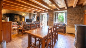 A rustic interior with exposed wooden beams, stone walls, a fireplace, and a stone fireplace. - Grand Gîte La Panouse en Margeride (LA PANOUSE)