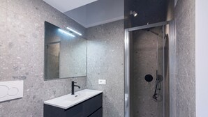 Une salle de bain moderne avec un lavabo blanc, un robinet noir et un grand miroir.