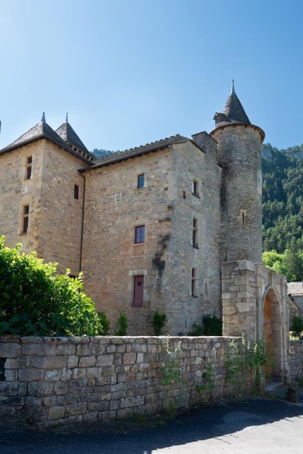 A stone castle with a tower, arched entrance, and a paved path. - L'OUSTAL DE LUCIE - SAINT SATURNIN (SAINT SATURNIN)