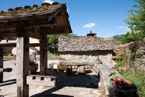 A rustic stone building with a tiled roof, a wooden pergola, and a stone bench. - L'OUSTAL DE LUCIE - SAINT SATURNIN (SAINT SATURNIN)