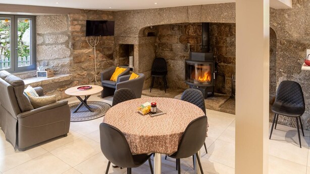 Ein gemütliches Wohnzimmer mit Steinwänden, einem Kamin, bequemen Sitzgelegenheiten und einem Fernseher.