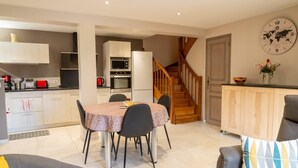 Eine moderne Küche mit Essbereich, einer Treppe und einem Wohnzimmer mit Sofa und Zierkissen.