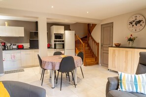 Eine moderne Küche mit Essbereich, einer Treppe und einem Wohnzimmer mit Sofa und Zierkissen.