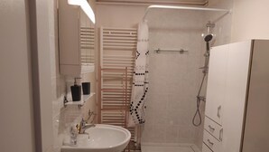 A bathroom with a sink, mirror, towel rack, shower, and storage cabinets. - Gîte Le Toura 2/4 persons (SAINT-ALBAN-SUR-LIMAGNOLE)