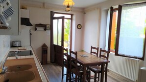 A kitchen with a sink, stove, and dining table with chairs. - Gîte Le Toura 2/4 persons (SAINT-ALBAN-SUR-LIMAGNOLE)