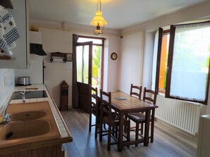 A kitchen with a sink, stove, and dining table with chairs. - Gîte Le Toura 2/4 persons (SAINT-ALBAN-SUR-LIMAGNOLE)