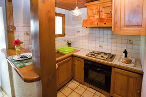 Eine Küche mit Holzausstattung, einem Gasherd, einem Geschirrspüler und einem Fenster.