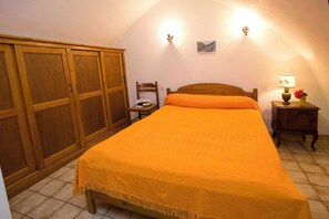 Ein Schlafzimmer mit Bett, Holzschrank, Stuhl, Nachttisch und Wandlampe.
