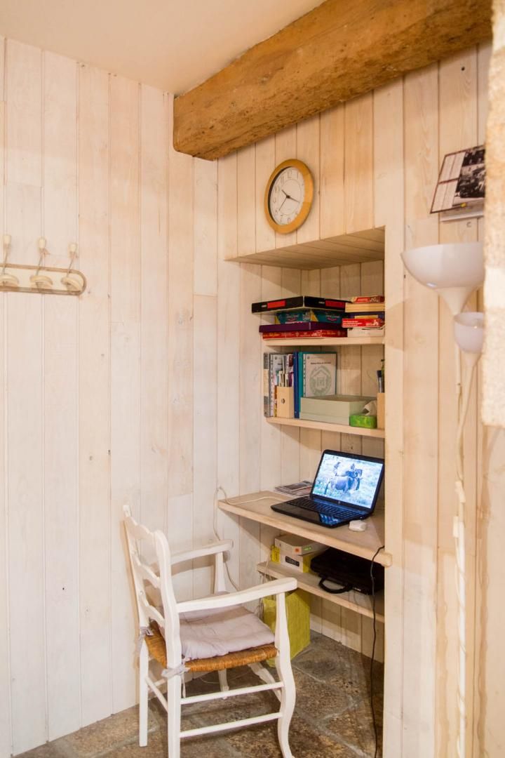 A wooden-paneled room with a desk, chair, and a clock on the wall.
