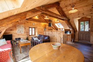 Ein gemütliches Holzinterieur mit rundem Tisch, Ledersofa und Essbereich.