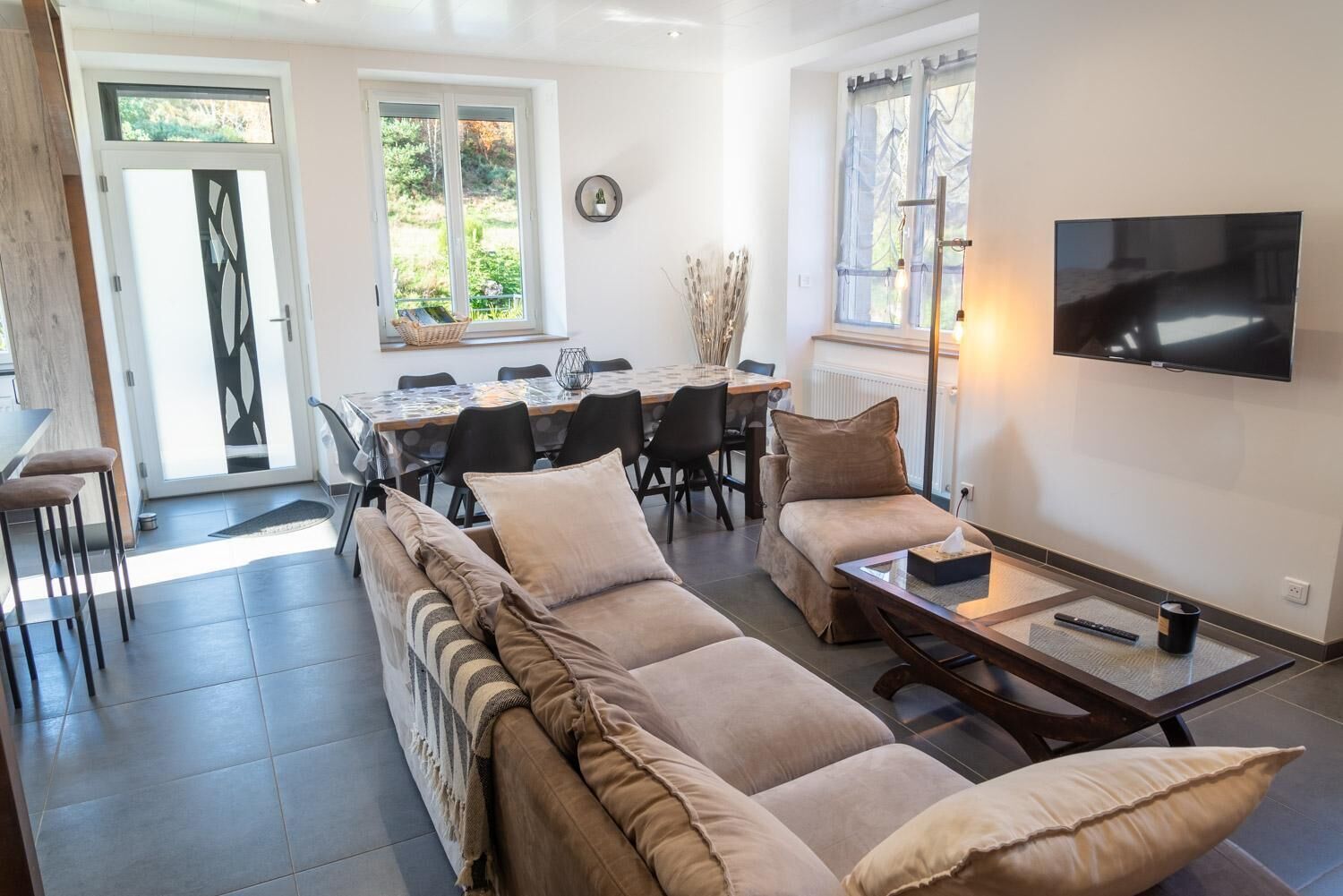 A living room with a sofa, a dining table with chairs, a TV, and a window.