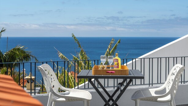 Un balcone con un tavolo, due sedie e vista sull'oceano.
